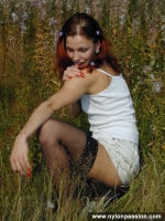 Teen redhead in black stockings posing outdoor